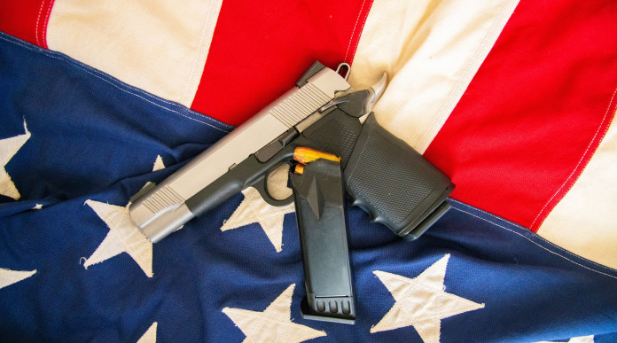 Come sta andando il mercato delle armi in America? pistola su bandiera americana, con caricatore di scorta